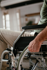 Close up of man holding wheel of wheelchair. Young disabled man in a wheelchair.