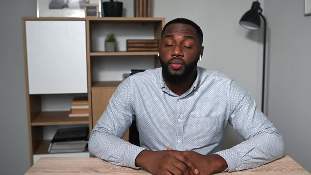Confident young African-American guy has online video meeting, looking at webcam and listening, he nods his head a sign of solidarity and agreement. Video chat with a multiracial businessman