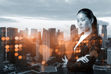 Attractive young Asian HR director at international company is thinking about recruitment of highly qualified specialists. Women in business concept. Social media hologram icons over Singapore.