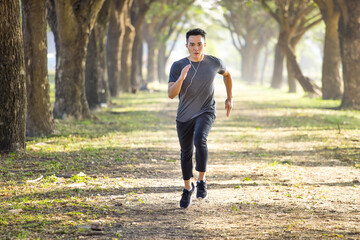 Asian young Man running in the forest on  foggy at  morning