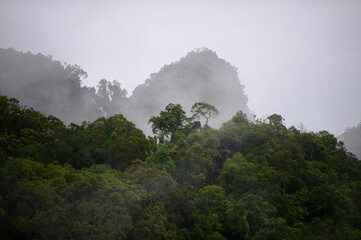 Mountain range with visible silhouettes through the morning colorful fog with cloud sky