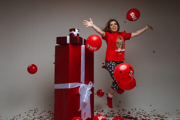 Portrait of jovial brunette in pajamas jumping with outstretched arms with balloons in the air....
