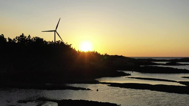 Drone video showing red sunset and windmills and trees and sea