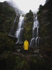 Young man in yellow jacket in front of El Chorro de Giron waterfall cascade cataract near Cuenca...