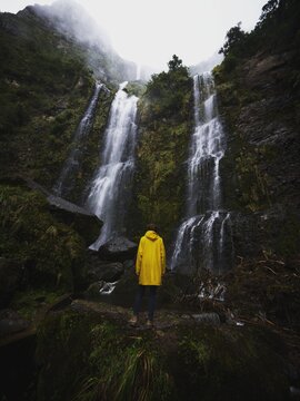 Young man in yellow jacket in front of El Chorro de Giron waterfall cascade cataract near Cuenca Azuay Ecuador