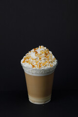 Caramel latte with cream on a black background.