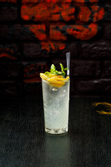 Alcoholic cocktail with mint and lemon in a glass on a black table