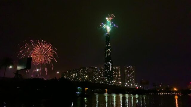 High resolution footage of colorful fireworks of Ho Chi Minh City at new year 2021 view from Landmark 81 riverside. Landmark 81 is the tallest building in Vietnam