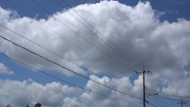 A video showing the blue sky, big clouds, power poles and electric lines.