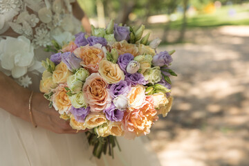 The bride is holding a cute wedding bouquet of roses.