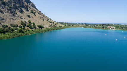 Fototapeta premium Beautiful scenery of the island from a bird's-eye view. Kataramarans sail along a blue lake against the background of green mountains and the city.