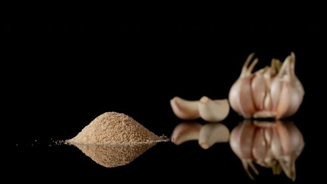 Garlic powder appearing near to garlic cloves, stop motion
