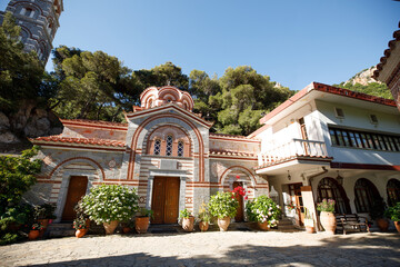 Obraz premium A view of the road and a beautiful ancient temple surrounded by flowerpots with flowers and greens.