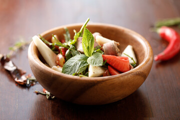 Fruit salad in a wooden bowl on the table.