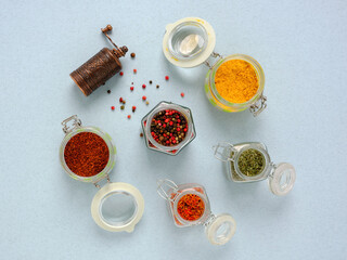 A closeup of glass containers with brightly colored spices and a hand mill