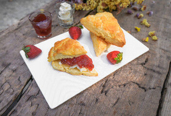 Scones and Strawberry Jam, Clotted cream in a white plate on a wooden table