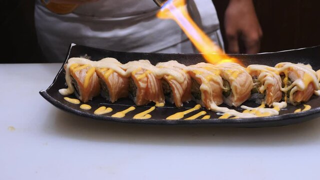 Japanese food  making SALMON ABURI SUSHI .
chef grill  fresh  salmon  maki roll. handheld shot close-up to hands.