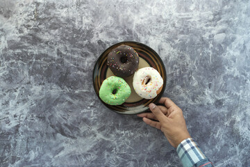 top view of hand holding a plate of donuts .