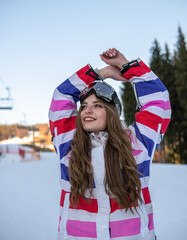 Portrait of Happy Pretty Caucasian woman in ski outfit and With Snowboarding Mask on her Head. Portrait of cheerful blond woman at ski resort