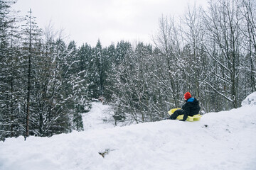 Niño de espaldas con un trineo en el monte nevado. 