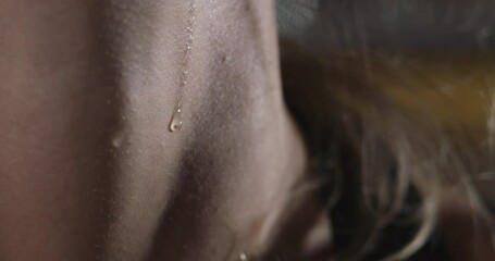 A macro shot is showing a drop of sweat gliding slowly down the throat of a blonde woman after she worked out. - Powered by Adobe