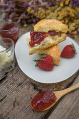 Scones with Clotted cream and Strawberry Jam  in a white plate on a wooden table.