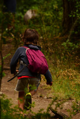 boy running through the forest with his backpack