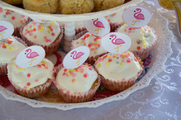 Close-up of homemade cupcakes with pink flamingo sticks decoration on a plate, party concept, sweets for birthday celebration, selective focus