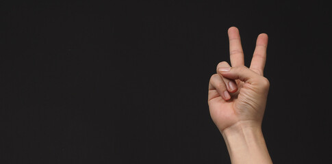 Hand is doing Victory or Peace hand Sign on black background.isolated and copy space.