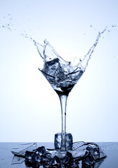 Splashes of water. Drop ice cubes into a wineglass with clear water