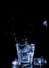 Glass with water and ice cubes on a black background