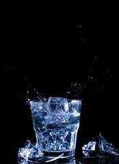 Glass with water and ice on a black background