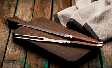 Fork and knife for meat on the board close-up