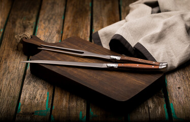 Fork and sharp knife for meat on the board close-up