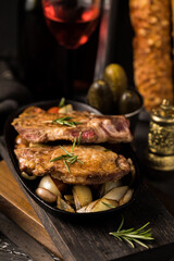 Tasty food. Frying pan with fried meat and onions, gherkins and French crispy baguette