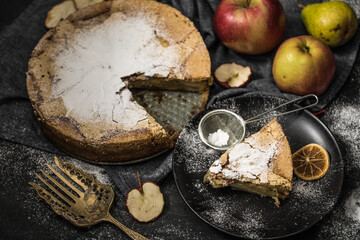 Delicious apple pie in a plate on a table with fruit