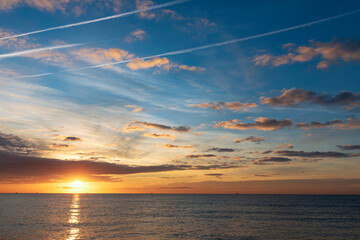 Sunrise over the Mediterranean Sea. Blue sky, sunlit clouds and traces of the aircraft flight. Spain, Barcelona.