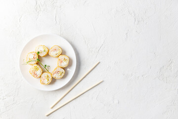 Sushi rolls on a white plate with chopsticks. Horizontal orientation, copy space, top view.