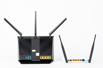 Rear view of  two Wi-Fi  routers, wireless devices with two  and three antennas.  Black router has  five Gigabit Ethernet ports, ultrafast USB 3.1 port and  USB 2.0 port. 
