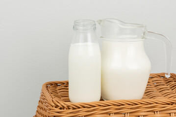 A jug and bottle of fresh milk glass on wooden basket background.Raw milk is high in calcium and protein to drink for all ages..Milk consumption nutritious and healthy dairy products concept.
