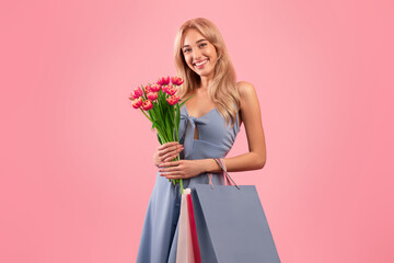Portrait of pretty young lady with bouquet of tulips and gift bags shopping for spring holiday,...