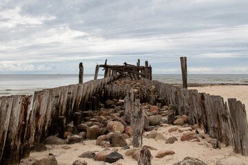 old dilapidated breakwater pier, made of wood and stone, on the shores of the baltic sea