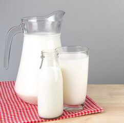  A jug and bottle of milk glass on a wooden table on background..Raw milk is high in calcium and protein to drink for all ages..Milk consumption nutritious and healthy dairy products concept..