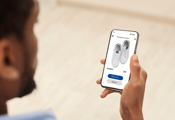 Black man using smartphone browsing online fashion store website