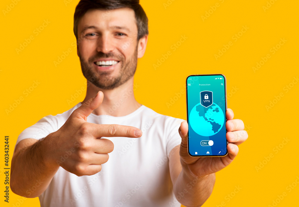 Poster smiling man holding and showing smartphone with vpn app