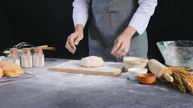 Baker throws yeast dough on a wooden tray for kneading the dough.