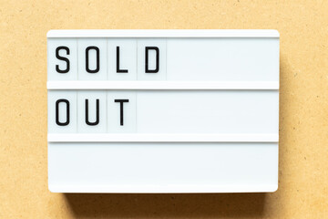 Lightbox with word sold out on wood background