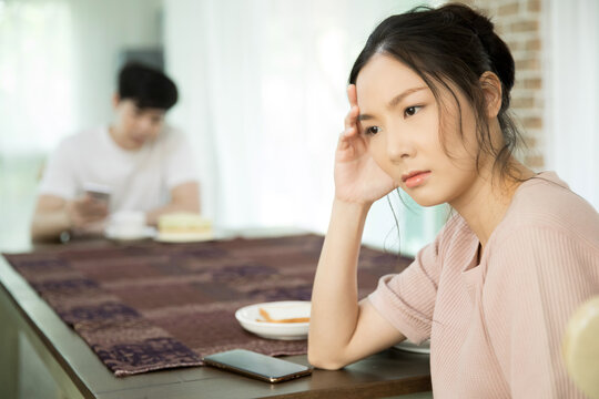 Young woman feeling upset during meal with husband at home dining table