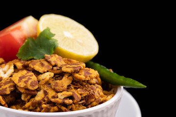 Close Up Of Healthy Flattened Bengal Chana Daal Chatpata Namkeen Masala Chana Jor Zor Garam Served With Lemon Tomato Green Chilly And Coriander Leaf. Isolated On Black background With Space For Text