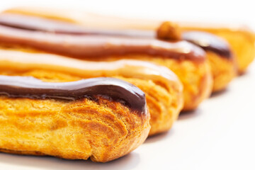 French eclair pastry on white background. Very shallow depth of field with focus on front chocolate eclair. Art concept.